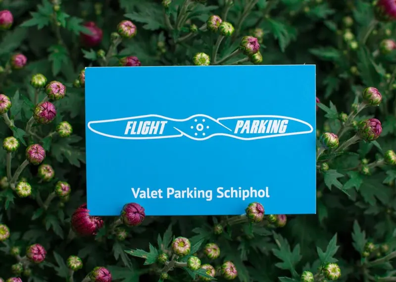 Blauw FlightParking-bord met de tekst Valet Parking Schiphol tussen bloemen